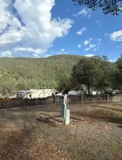 Utility pedestal on a gravel pad with RVs and a forested hill behind