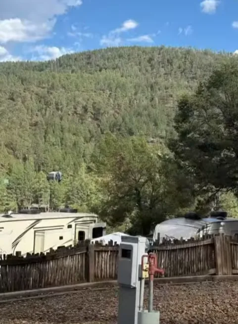 Utility pedestal in the foreground with RVs below a forested hill