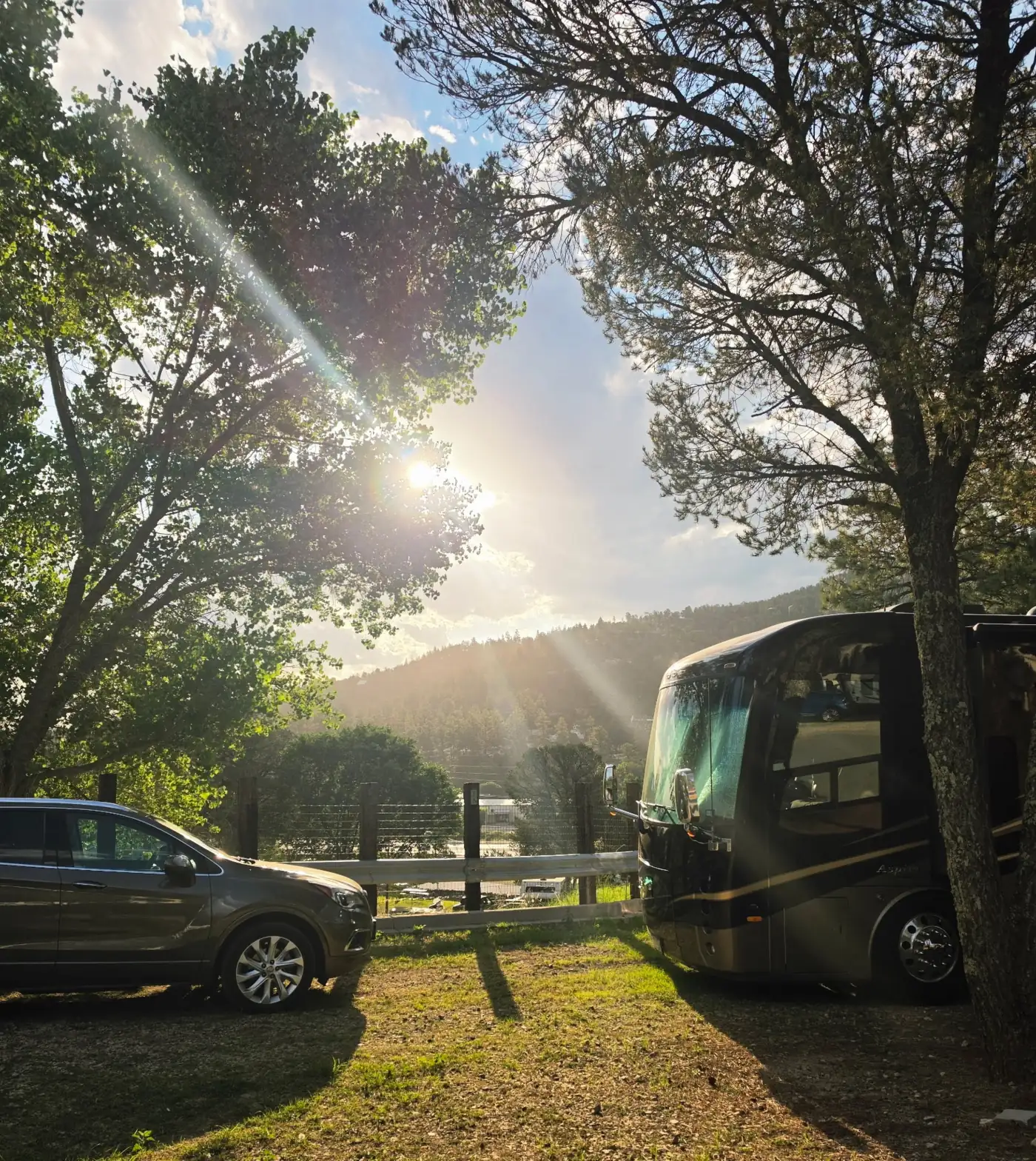 A motorhome at its site as the evening sun drops behind the ridge